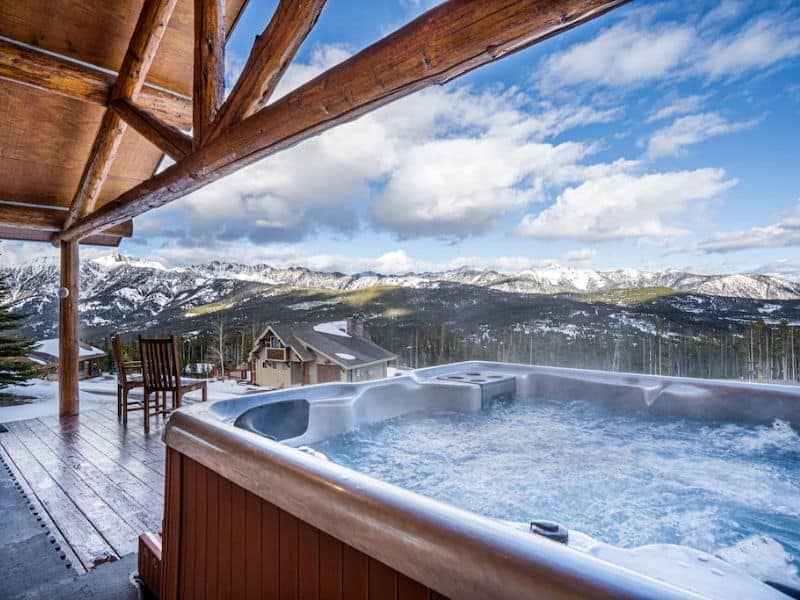 Inviting outdoor hot tub on the deck of a ski in ski out Big Sky MT rental, offering panoramic views of the Montana mountains and ski slopes.
