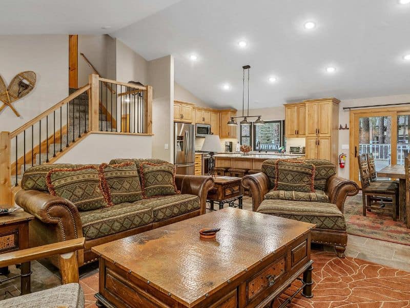 Cozy living room in a Big Bear cabin with plush sofas, a large stone fireplace, and a dartboard.