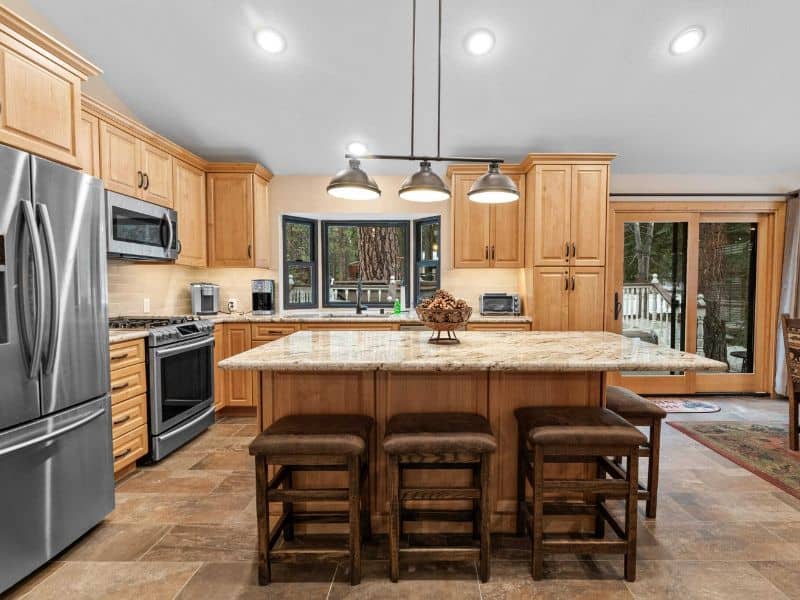Spacious Big Bear cabin rental kitchen with modern appliances and a central island with bar stools, featuring warm wooden cabinetryt.
