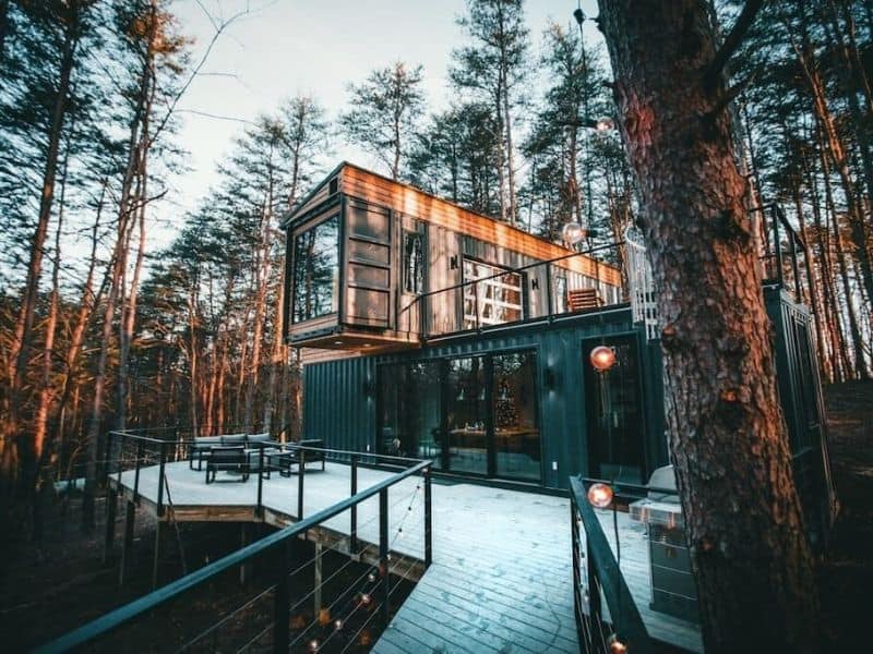 Container cabins in the woods with a deck.