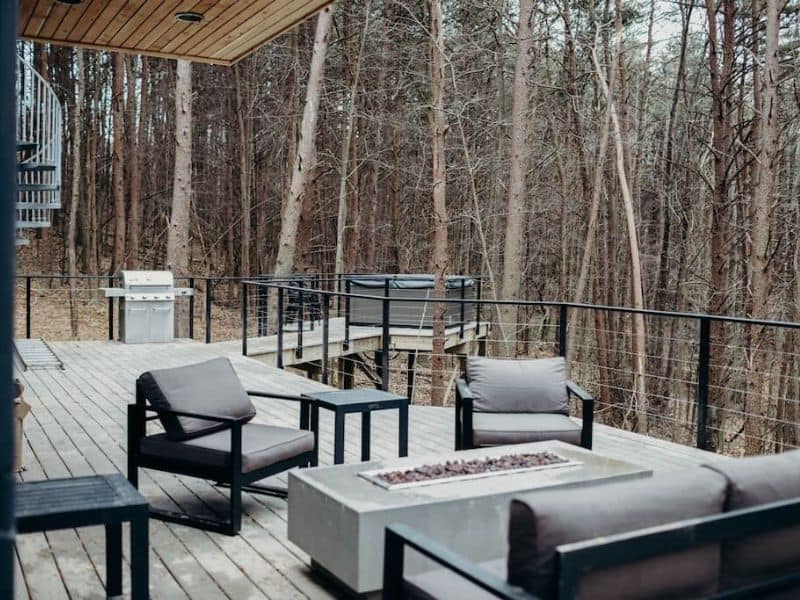 Container cabins with furniture and a fire pit in the woods.