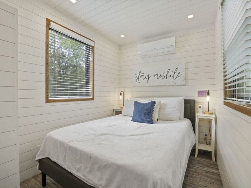 A bedroom in a tiny house with a bed and a window, located in container cabins in Hocking Hills.