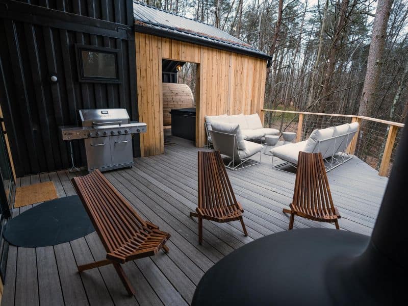 A deck with chairs and a grill in the woods near container cabins in Hocking Hills.