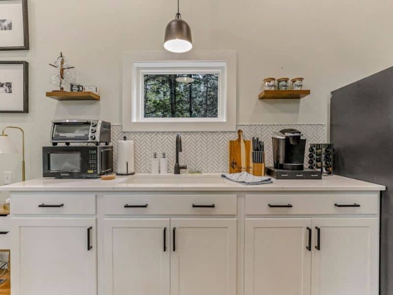 Compact and efficient kitchen space in The Nook, a Hocking Hills container home, with modern appliances and herringbone backsplash.