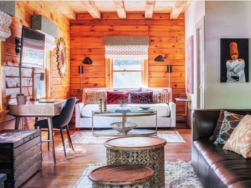 Bright and airy living space inside a cozy Catskills cabin rental, with a plush white sofa, patterned cushions, and a unique sunburst mirror.