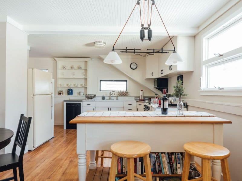 Open kitchen with clean white subway tiles and wooden accents in a Catskills Vrbo rental, with a farmhouse sink and a breakfast bar with stools.