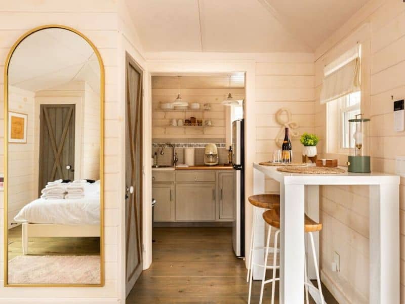Compact and efficient kitchen space in a cozy Catskills cabin rental with white cabinetry, wooden countertops, and bar seating under unique pendant lighting.
