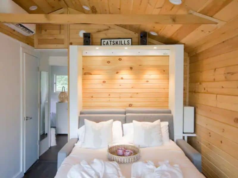 Bedroom inside a cozy Catskills cabin rental with a Murphy bed set against a wooden wall, flanked by speakers and ambient lighting.