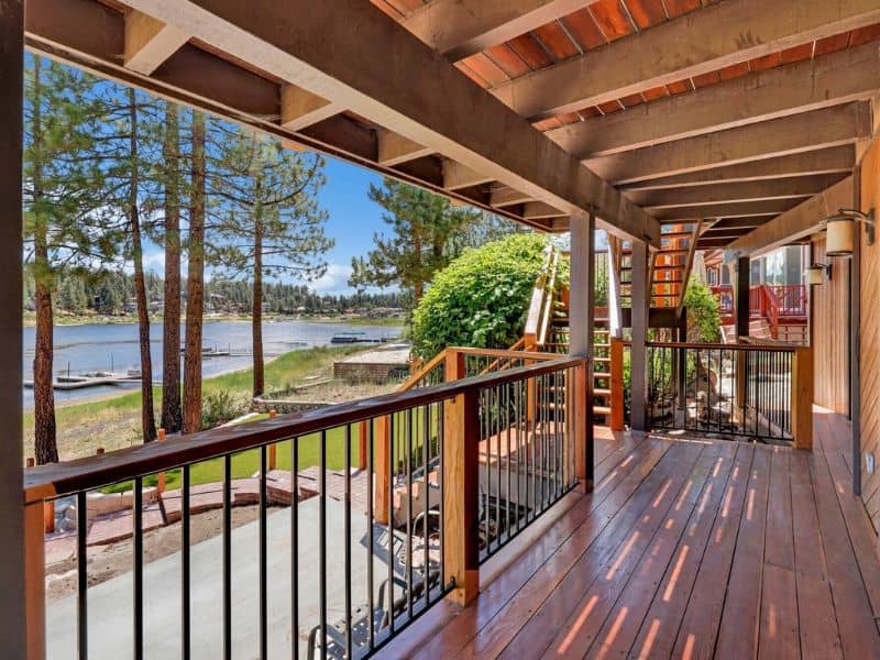 Deck view from a lakefront cabin rental in Big Bear, showcasing a clear view of the lake and surrounding pine trees.