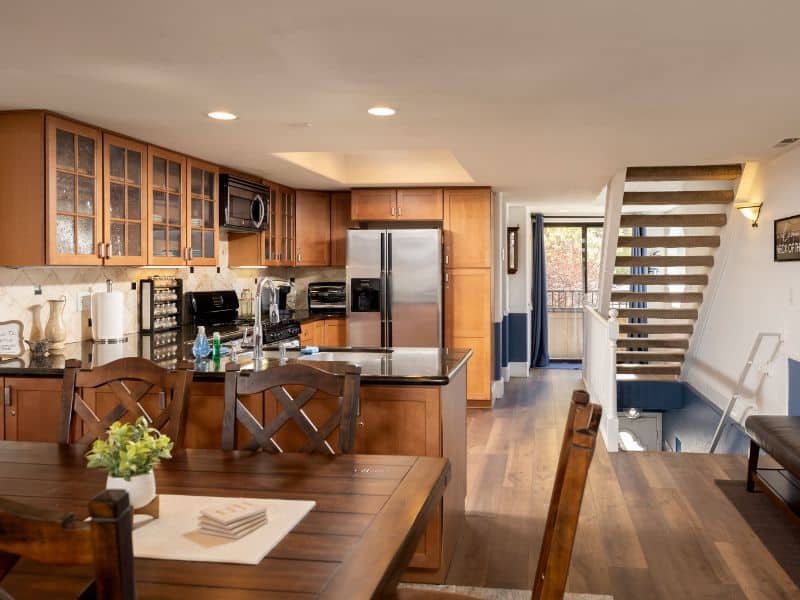 Spacious kitchen with wooden cabinets, stainless steel appliances, and a dining area in a Big Bear condo.
