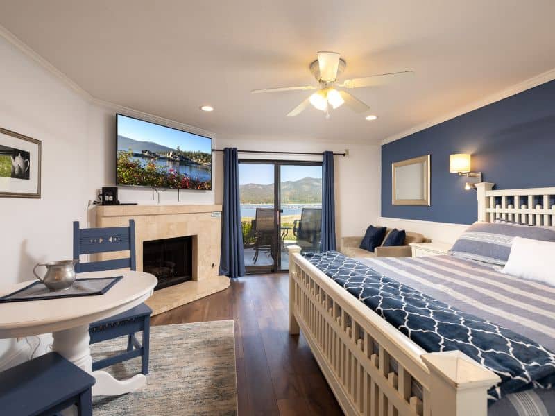 Master bedroom in a Big Bear lakefront condo, complete with a king-size bed, ensuite fireplace, and a balcony overlooking the lake.
