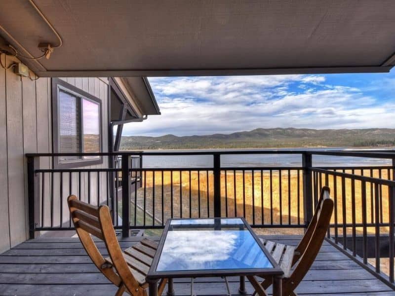 Balcony view from a Big Bear CA Vrbo rental, showcasing wooden outdoor chairs and a table.