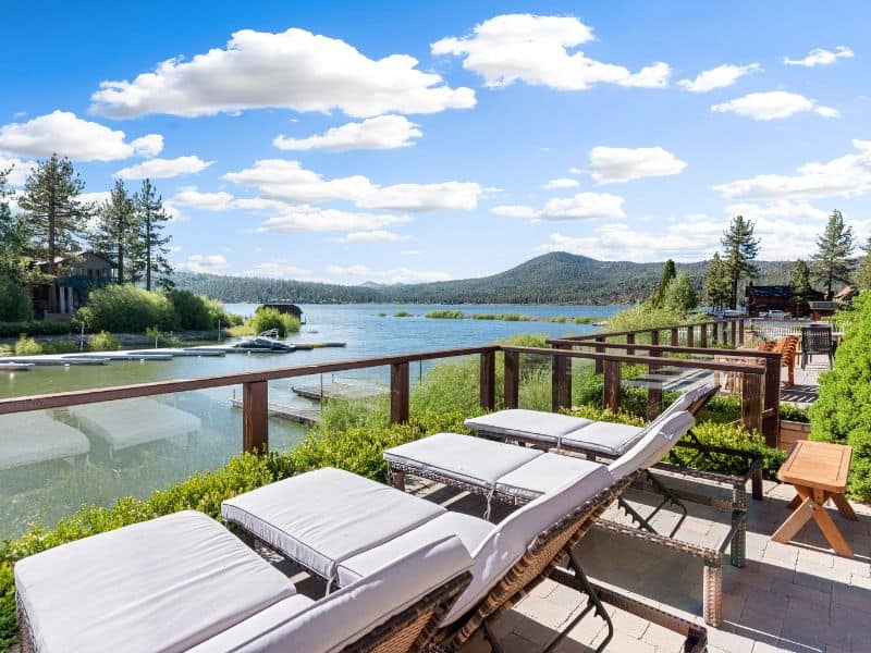 Lakeside deck with lounge chairs and umbrellas at a Big Bear lakefront cabin rental.