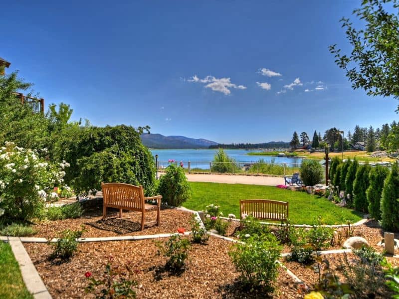 Garden bench in the landscaped yard of a Big Bear Vrbo rental, overlooking Big Bear Lake and mountains in the distance.