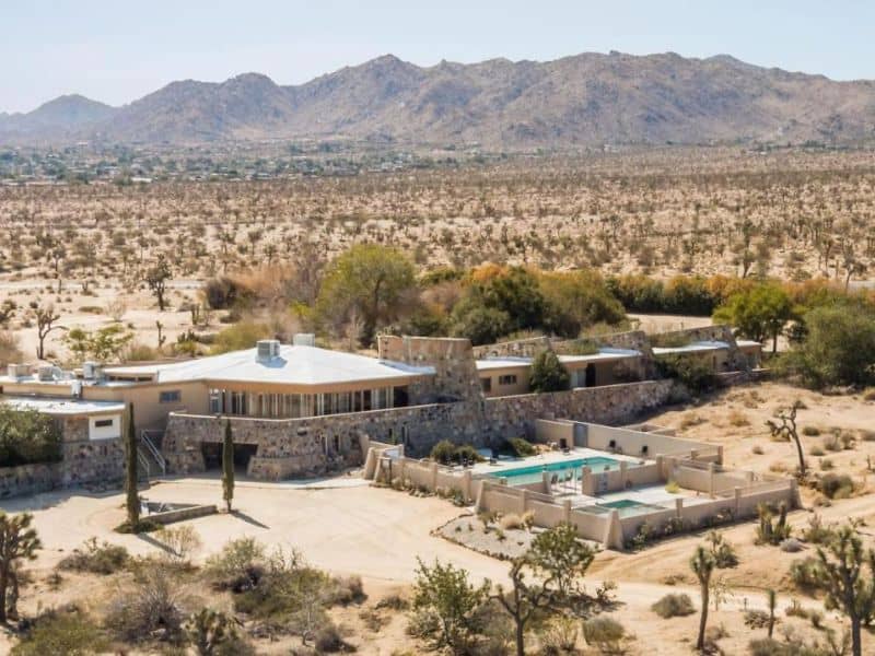 Aerial view of Joshua Tree Retreat Center campus set amidst the vast desert landscape, complete with a central pool and multiple units for an immersive retreat experience.