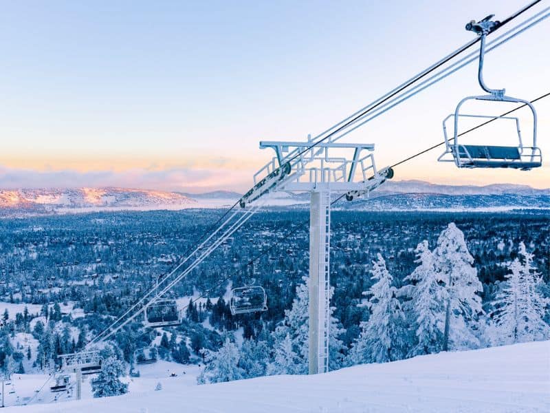 Ski lifts in Big Bear california at dawn with snow covered background.