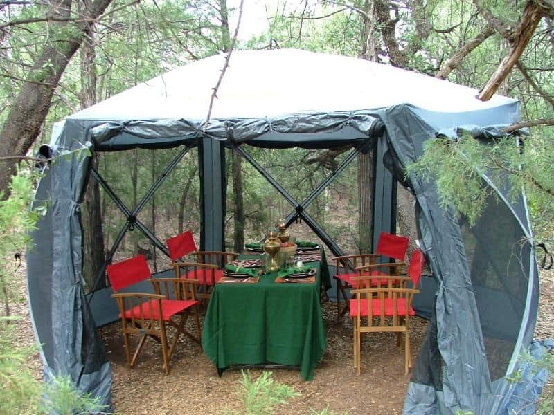 A screened dining tent set up by Arizona Luxury Expeditions amid pine trees, providing a rustic outdoor dining experience near the Grand Canyon.