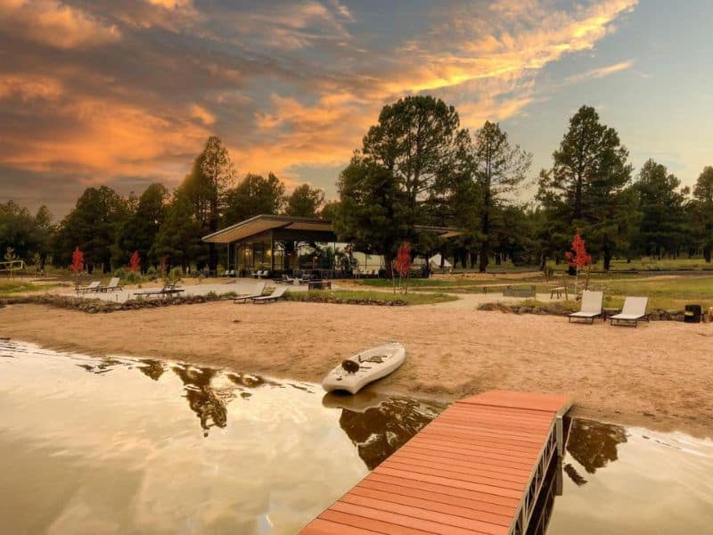 Sunset view of a peaceful lake with lounge chairs, part of the Backland glamping experience near the Grand Canyon.
