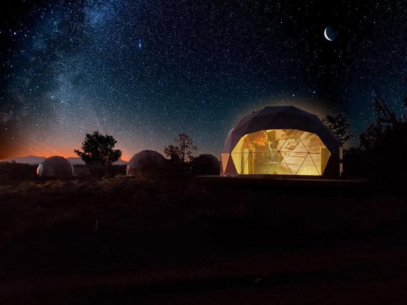 A glamping dome at Clear Sky Resorts Grand Canyon illuminated at night, under a star-filled sky. Luxury glamping near the South Rim.