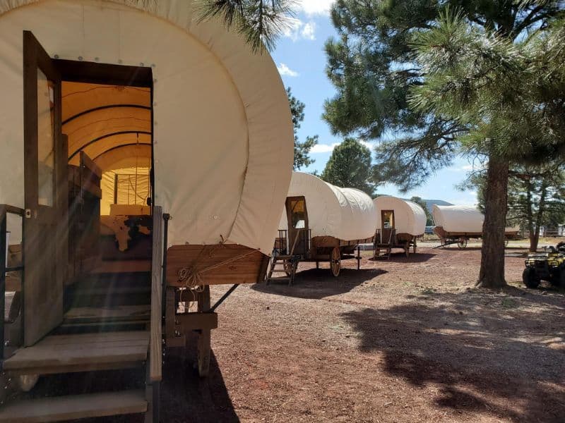 Covered wagon accommodation at KOA Williams with an open doorway showing a glimpse of the comfortable interior.