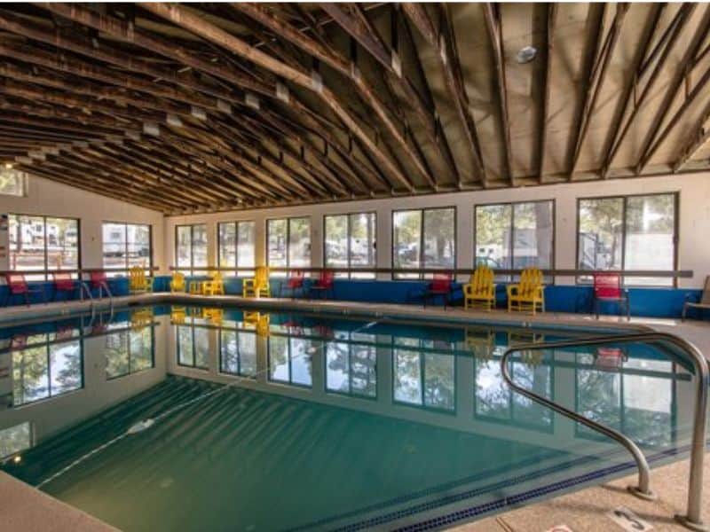 Indoor swimming pool at KOA Williams with ample seating, one of many amenities offered on-site.