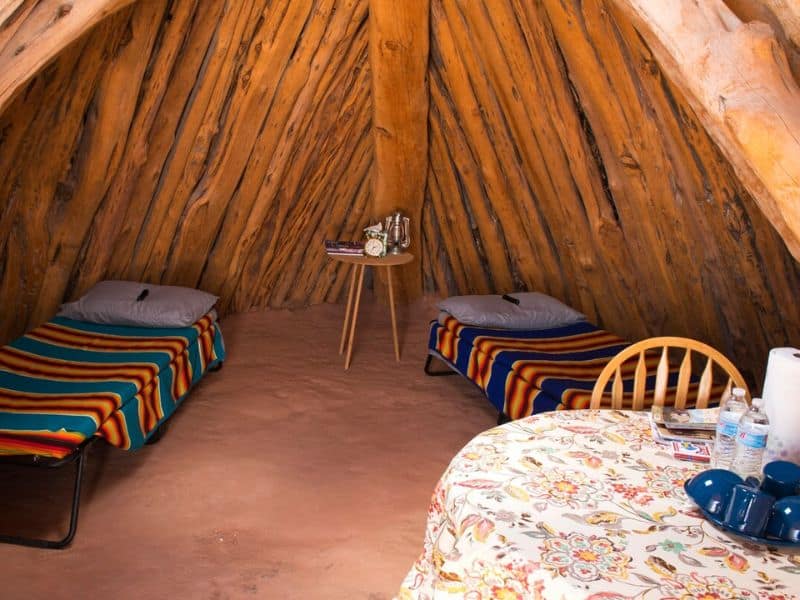 Inside view of a Navajo hogan with twin beds and rustic wooden furnishings. Rustic glamping near the Grand Canyon.