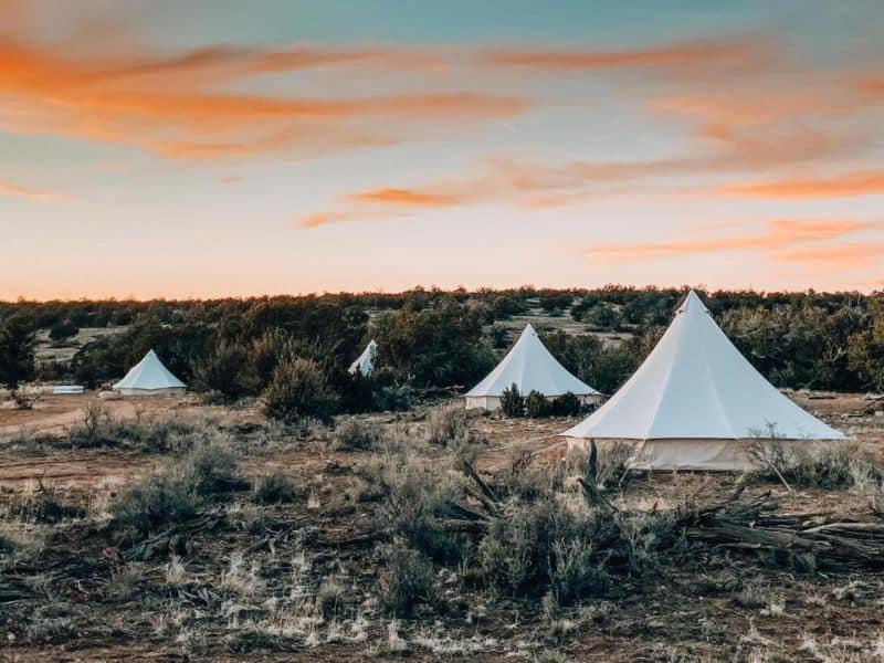 Wander Camp canvas tents dotting the landscape at dusk at sunset; a unique glamping experience near the Grand Canyon South Rim.