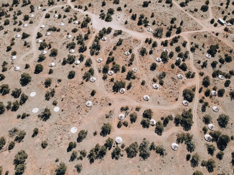 Aerial view of Wander Camp's glamping site showing the arrangement of white canvas tents amidst the desert terrain near the Grand Canyon.