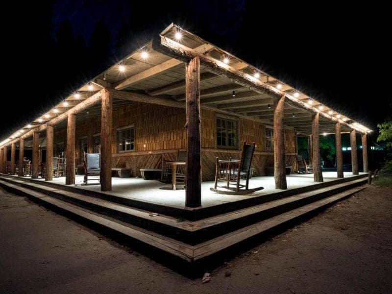 Nighttime scene of a wooden deck stretching around a shared recreational room at Curry Village in Yosemite National Park.