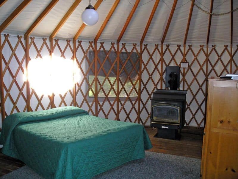 Rustic bedroom in a glamping yurt near Yosemite with a cozy bed and wood stove.