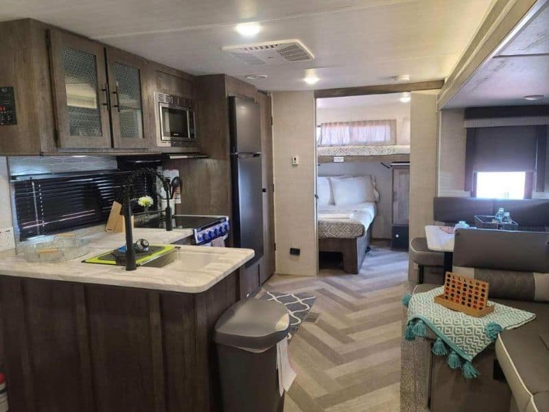 Interior view of a modern RV at Grand Canyon RV Glamping, with a kitchen area with appliances and a glimpse of the sleeping quarters.