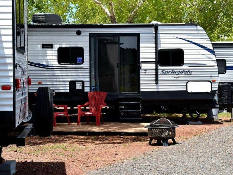 Exterior setup of an RV at Grand Canyon RV Glamping in Williams, AZ, featuring outdoor chairs and a fire pit for an authentic outdoor experience.