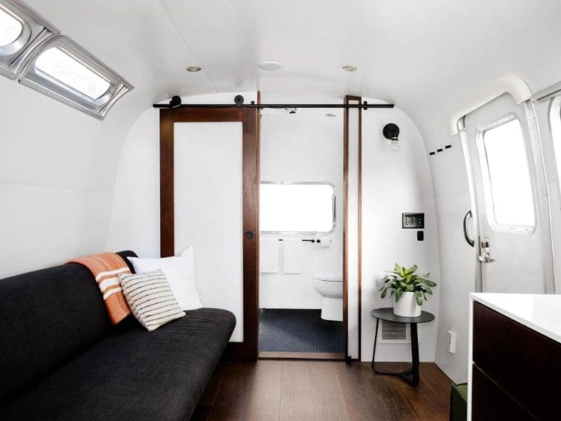 Lounge area inside an Airstream trailer leading to a compact bathroom at AutoCamp Yosemite in Midpines CA.