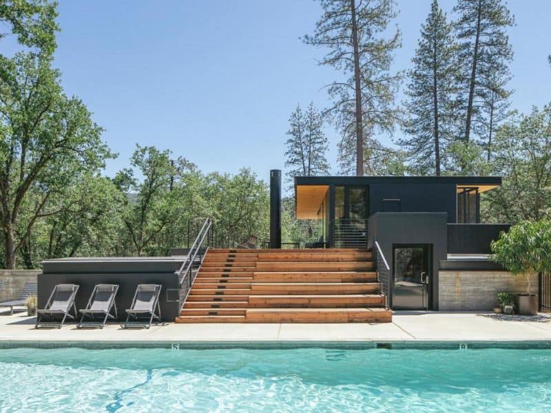 Poolside relaxation area with lounge chairs and a contemporary pool house at AutoCamp Yosemite in Midpines, CA.