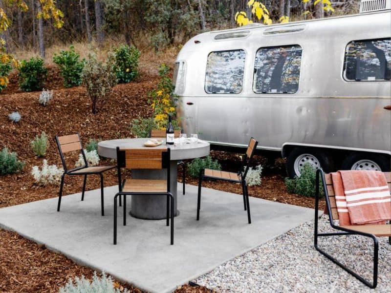 Outdoor dining setup adjacent to a sleek Airstream trailer at AutoCamp Yosemite, showcasing a luxurious glamping experience near Yosemite National Park.