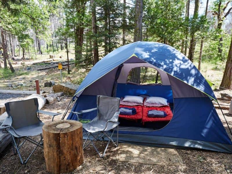 Open camping tent revealing cozy sleeping bags in a custom glamping site at Evergreen Lodge near Yosemite's Hetch Hetchy Entrance.