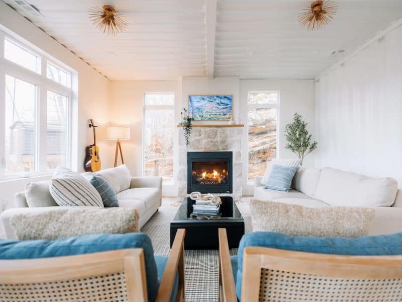 Cozy living room with a lit fireplace at The Overlook, with comfortable seating and natural light. Hocking Hills shipping container cabin rental.