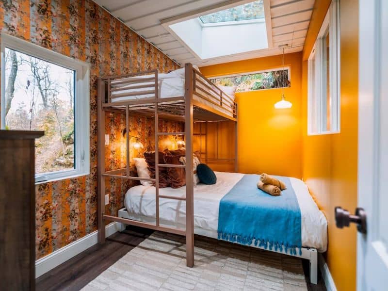 Bedroom setup inside The Roca Box Hop featuring a bunk bed and a skylight, combining functionality and design.