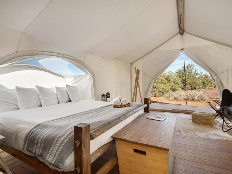 Interior of a luxurious Under Canvas glamping tent with a large bed and panoramic window view near the Grand Canyon.