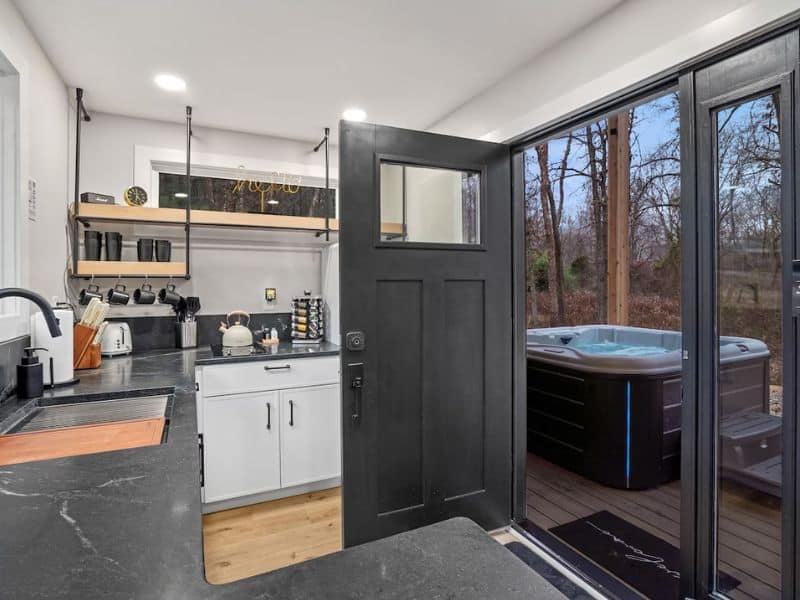 A Hocking Hills container home kitchen with an open door to an outdoor hot tub.