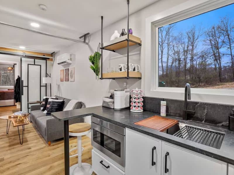 An open-concept living area inside a Hocking Hills container cabin, with a kitchenette and cozy sofa.