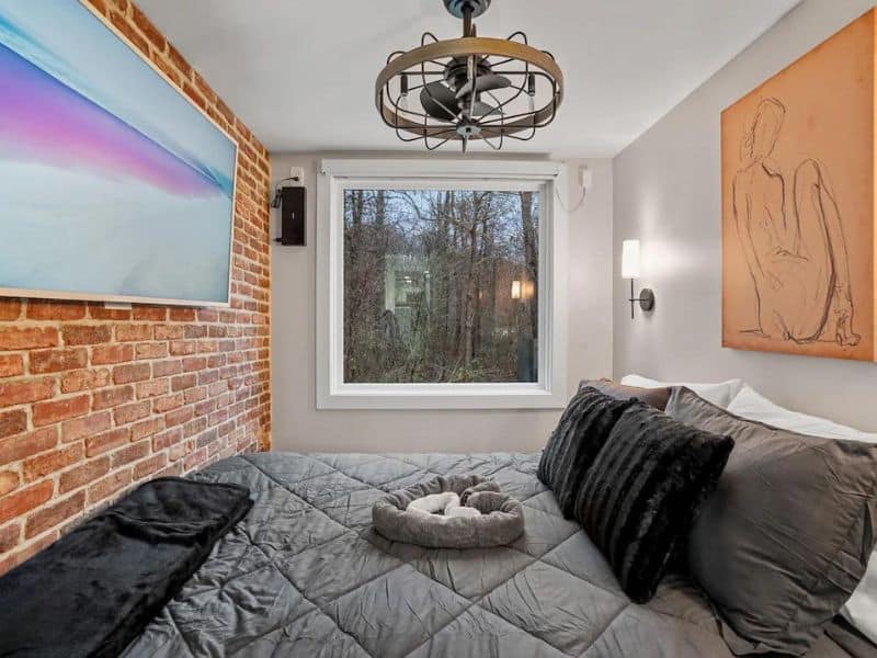 Minimalist bedroom with abstract artwork and a mounted smart TV at The Juice Box!, a container cabin in Hocking Hills.