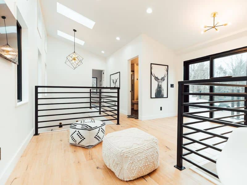 Spacious upper-level area in The Rohe Block, a Hocking Hills container home, with modern décor, a geometric light fixture, and framed artwork.