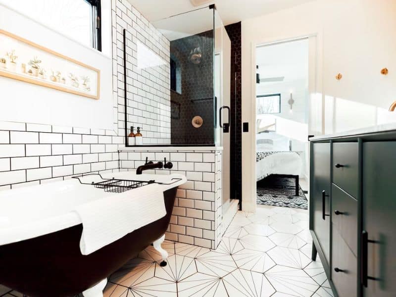 Elegant bathroom featuring a classic freestanding tub and a contrasting black-and-white tiled shower in The Rohe Block, a Hocking Hills shipping container cabin.