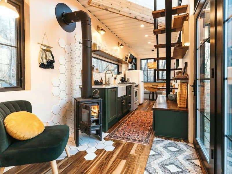 Cozy interior of The Boho Box Hop with a wood-burning stove, hexagonal tile wall, and comfortable seating. Hocking Hills Shipping Container Cabin.