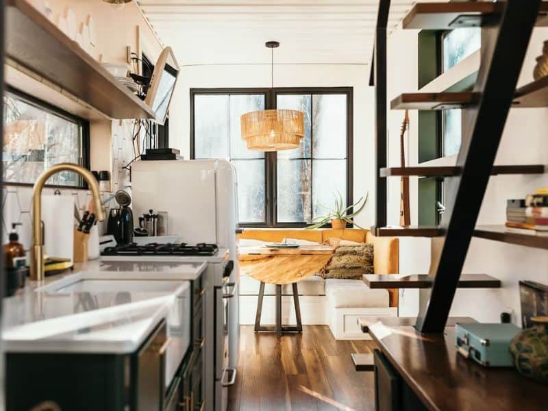 Compact kitchen space with retro appliances and a wooden dining nook inside a container cabin in Hocking Hills.