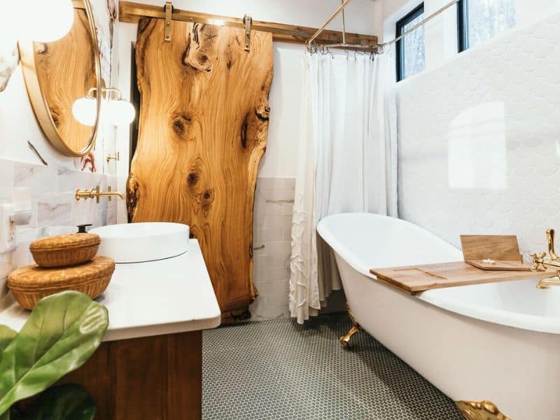 Rustic-chic bathroom with a unique wooden slab door and a freestanding tub in a Hocking Hills container home.