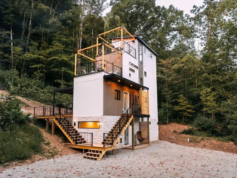 Exterior view of The Block Tower at dusk, showcasing a tiered design and outdoor spaces of this unique Hocking Hills container home.