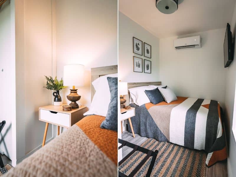 Cozy bedroom in Nova Cottage with a striped comforter and decorative pillows, accented by fern prints and a rustic wooden bedside table. Shipping container cabins in Hocking Hills, OH.