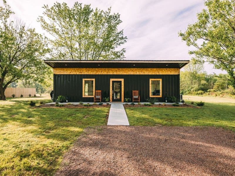 Front view of Nova Cottage, a container cabin in Hocking Hills, with a path leading to a porch framed by natural greenery.